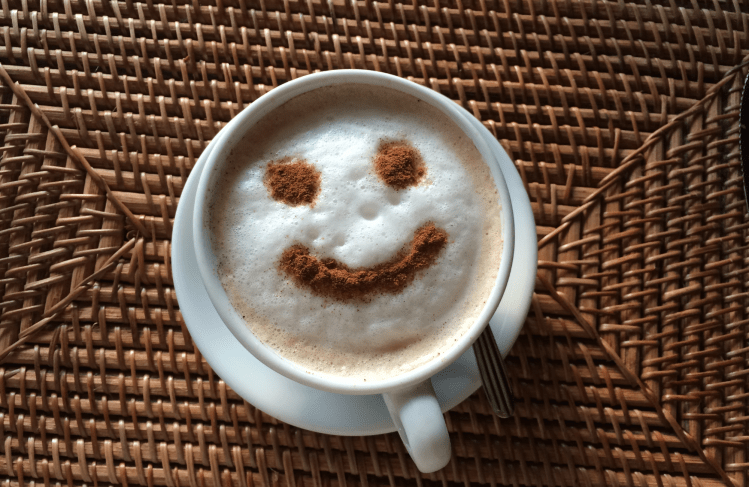 Coffee with froth, chocolate powder sprinkled into a smiley face.