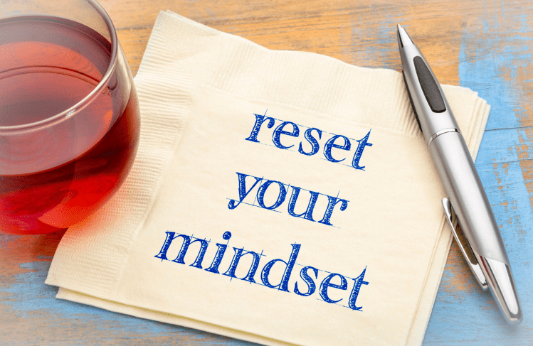 A tea, pen and napkin with "reset your mindset" written on it.