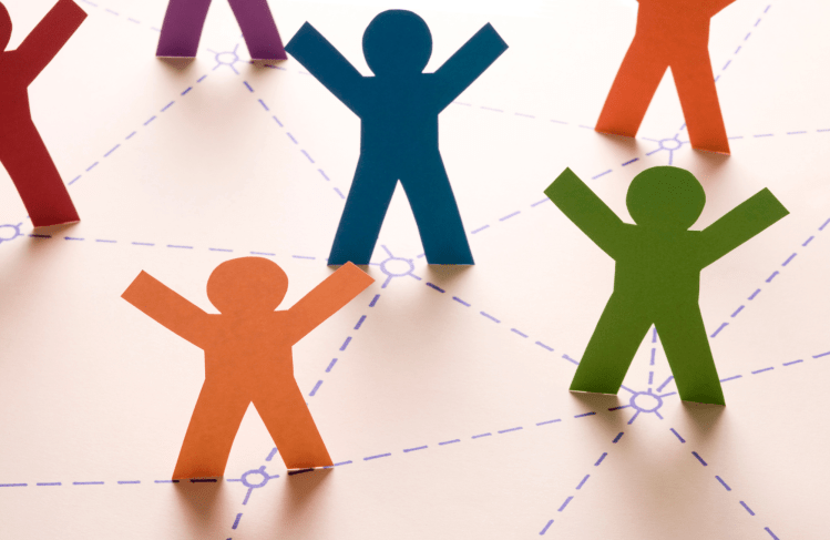 Paper cut outs of people standing together with their hands in the air, representing empowerment.