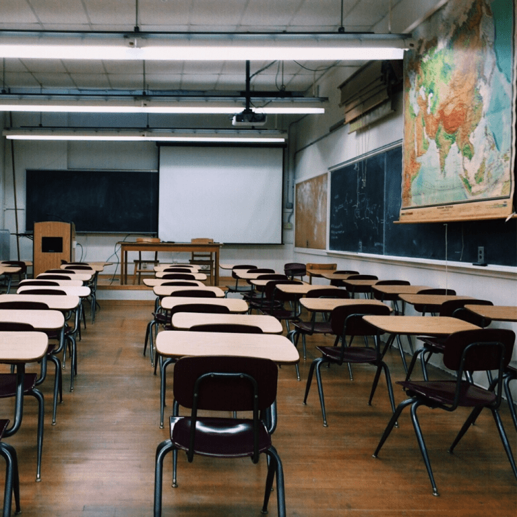 An empty classroom, desks, map and whiteboard.