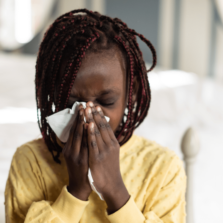Child blowing nose into tissue.