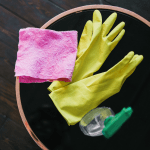 Yellow gloves, spray bottle and pink cloth, in a pot of soil.