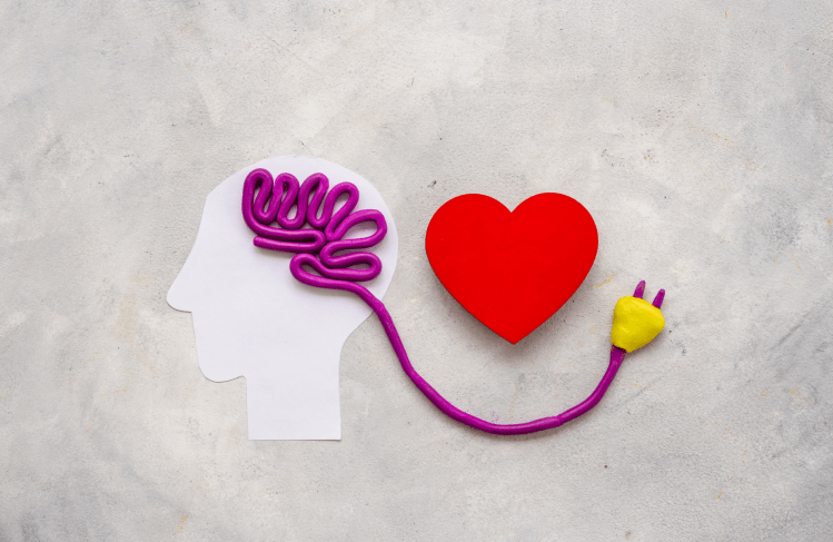 Simple paper and clay head with an electrical cord instead of a brain, plugged into a heart.