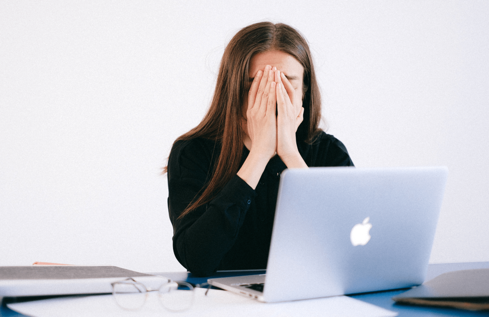 Woman with face in hands at a laptop.