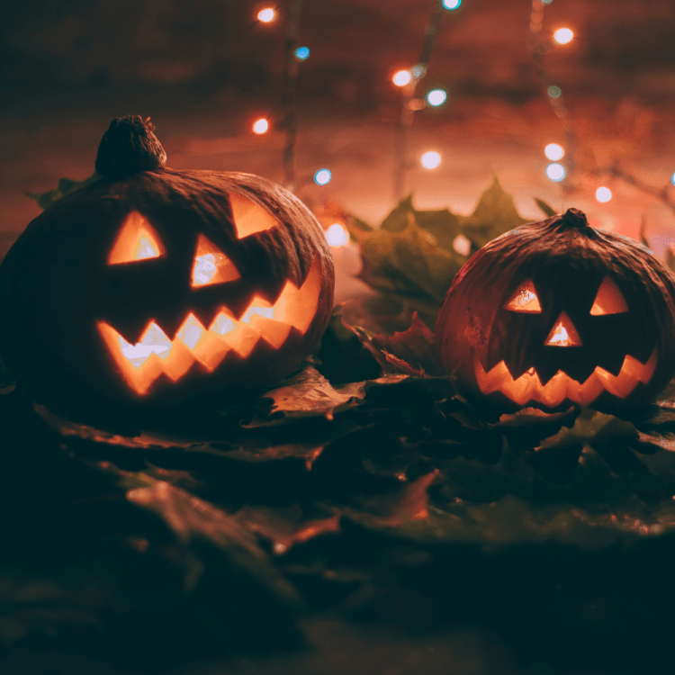 Jack-O-Lanterns lit up with fairy lights behind them.