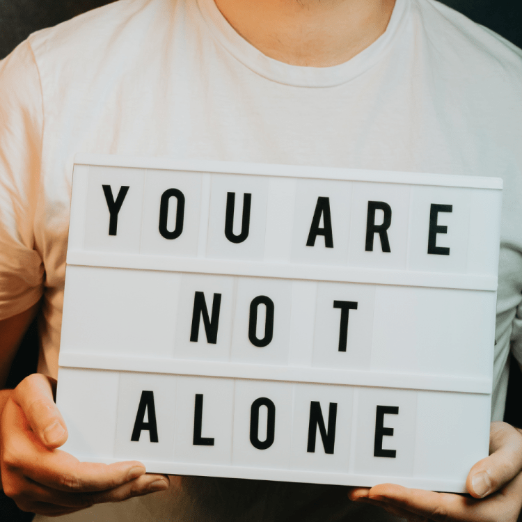 Man holding a sign that says "you are not alone". 