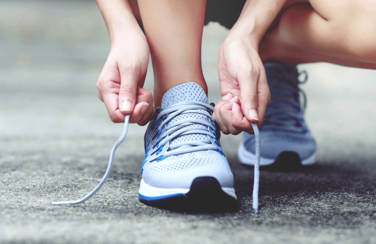 Hands tying up a running shoe.