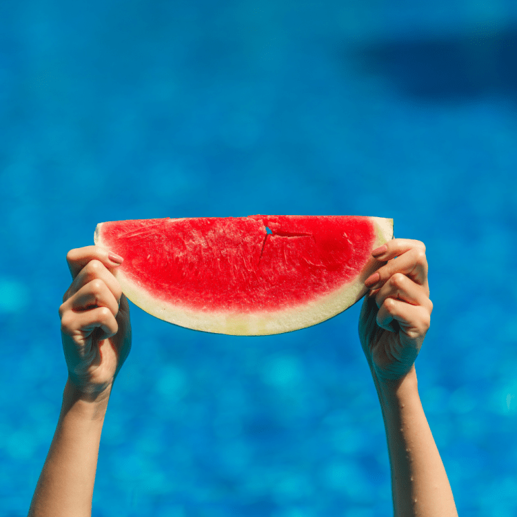 Seedless watermelon slice being held in the air.