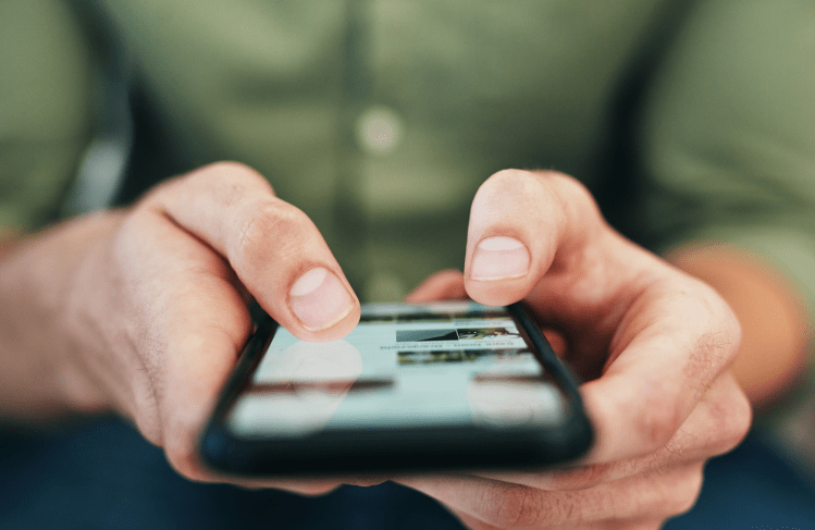 Hands holding iphone with thumbs scrolling the screen.