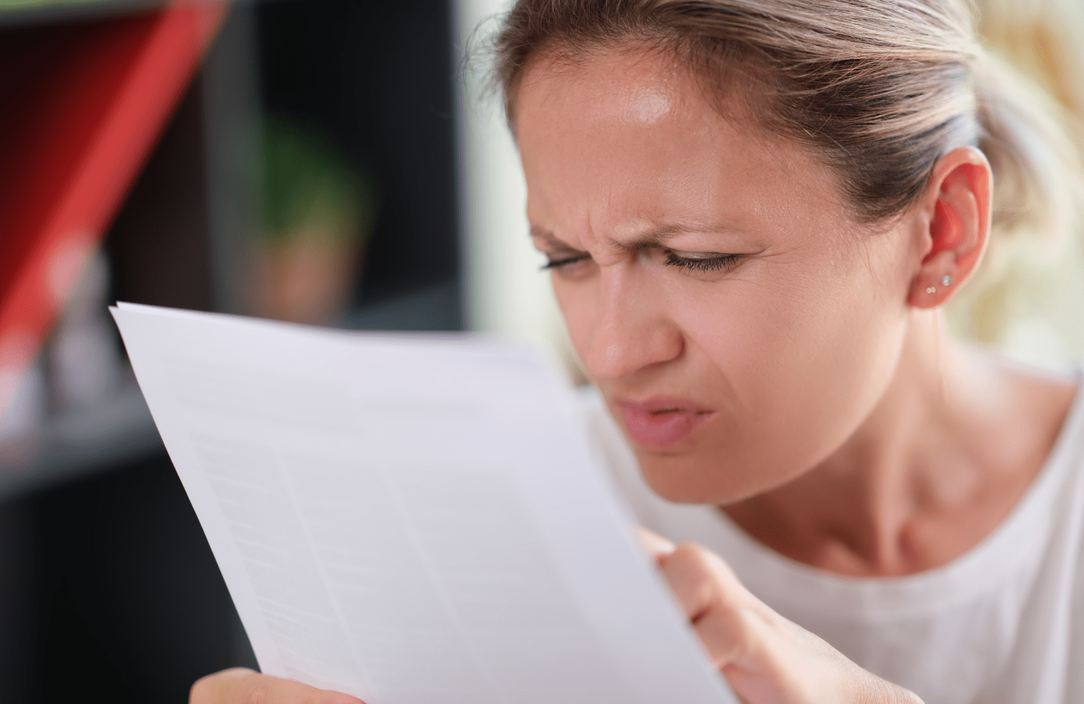 Woman squinting while looking at a piece of paper.